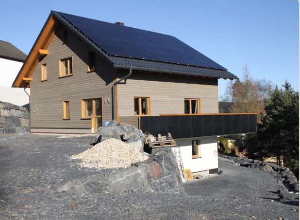 Holzhaus mit einer Solaranlage auf dem Dach vor blauem Himmel